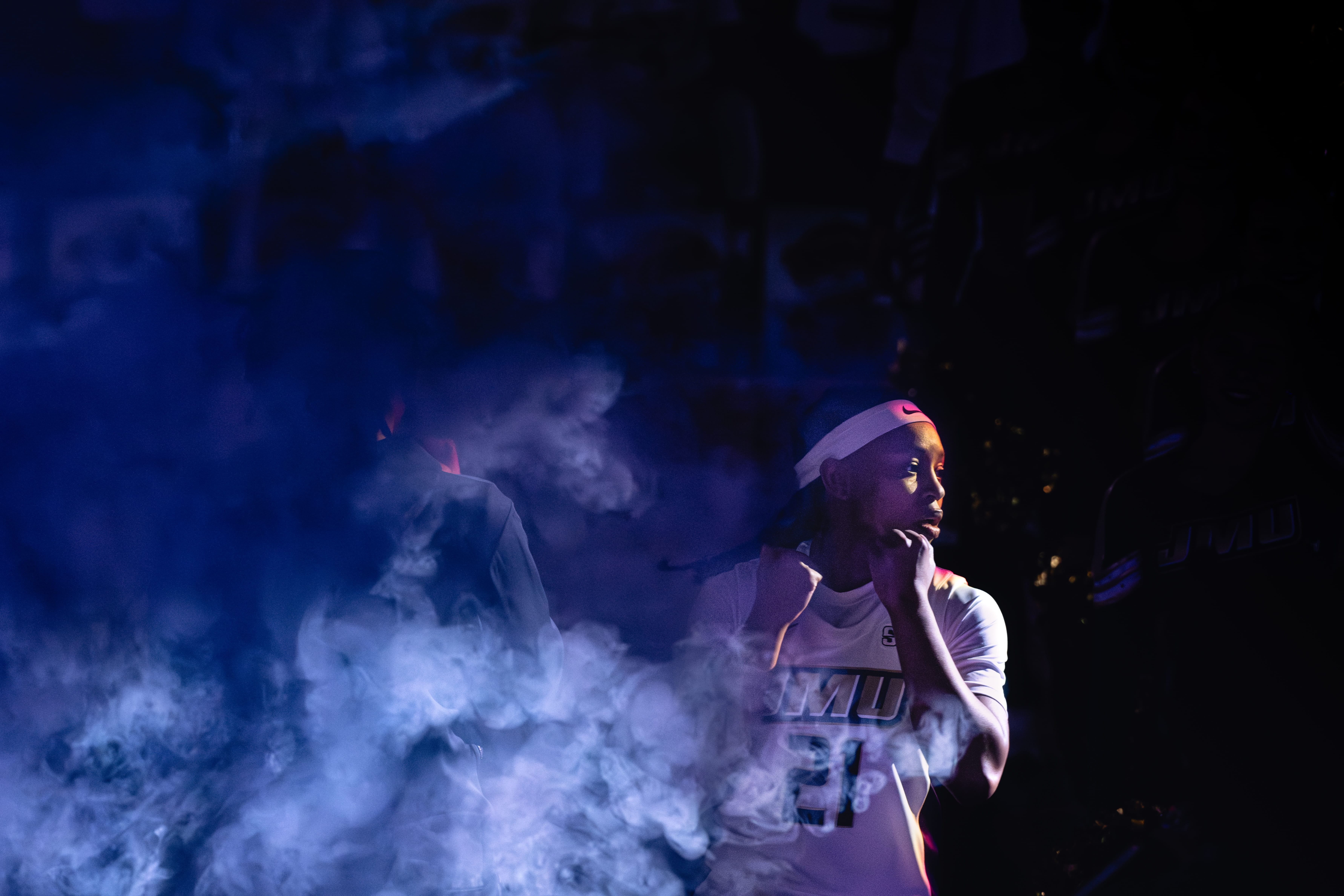 Basketball players emerging through blue smoke before a game